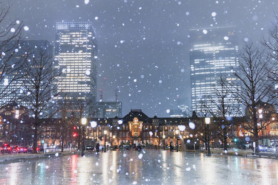 Snow falling outside the red bricked Marunouchi Building at Tokyo Station.